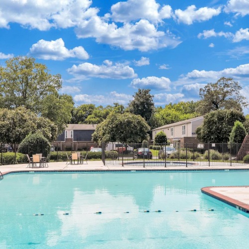 a swimming pool with trees and houses in the background